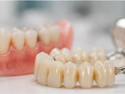 A denture and a dental bridge alongside dental instruments